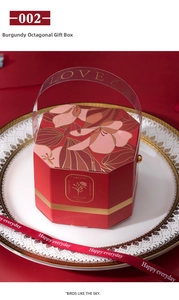 Detail of burgundy octagonal gift box with floral pattern and golden handle with ribbon
