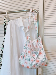 Detailed texture of white cotton tote bag with pink and orange floral prints on a hanger