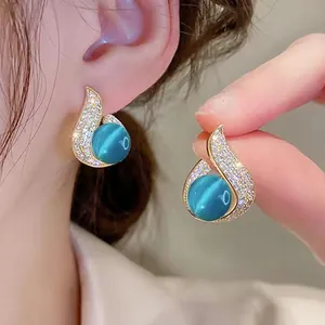 Detail of elegant flame earrings with blue cat-eye stone and micro-paved rhinestones