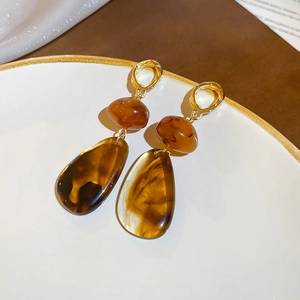 Close-up of vintage resin amber teardrop earrings with golden metal stud details