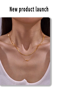 Gros plan d'un collier doré à deux rangs avec pendentif oiseau et perle sur modèle