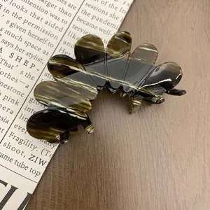 Elegant tortoiseshell acetate flower hair claw clip with marble pattern on a wooden background