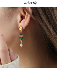 Detailed close-up of bohemian tassel earrings with natural malachite and pearl on a model