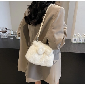 Detail einer flauschigen weißen Kunstpelz-Tasche an einem eleganten beigen Blazer