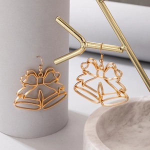 Gros plan de boucles d'oreilles cloche dorées ajourées sur support pour bijoux de Noël