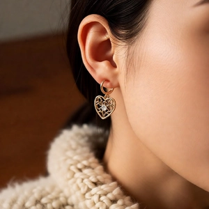 Detail of vintage heart key earring with zircon stone inlay on gold plated surface