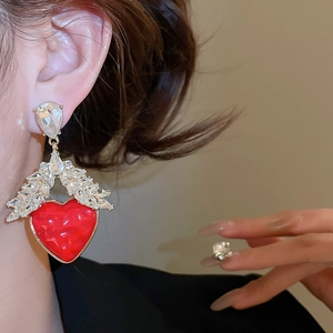 Vue détaillée de boucles d'oreilles cœur rouge avec strass portées par un mannequin