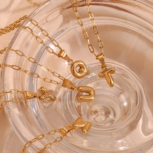 Close-up of 18K gold plated stainless steel necklaces with mini bubble letter pendants