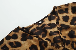 Detail eines Kleides mit Leopardenmuster, V-Ausschnitt und Etikett Größe M auf Stoff
