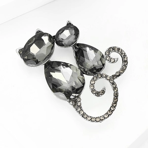 Macro shot of dark crystal cat brooch featuring sparkling rhinestones on textured white background