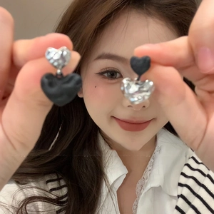 Asymmetric heart stud earrings with silver and black pleated texture shown on model