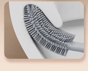 Flexible grey silicone toilet brush head cleaning rim of white toilet bowl close-up