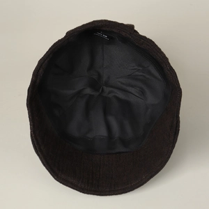 Internal detail of dark brown linen newsboy cap showing black lining and 100% linen label
