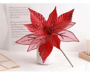 Close-up of red artificial poinsettia with glitter petals in a white vase for decor