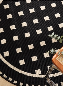 Close-up detail of thickened woven round rug texture with black and cream geometric pattern