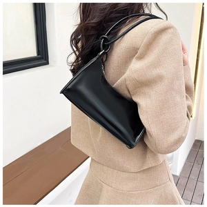 Detail of minimalist black baguette bag with glossy finish and knotted shoulder strap