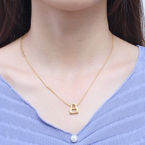 Elegant gold snake chain necklace featuring a heart-shaped lock pendant worn by a model
