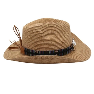 Detailed view of woven straw cowboy hat featuring ethnic embroidery and leather tassel