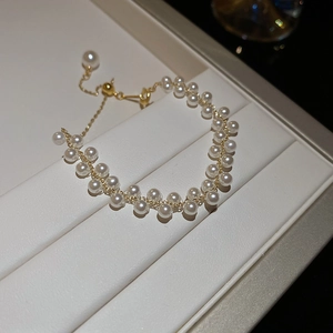 Détail d'un bracelet double rang de perles avec fermoir doré ajustable sur support cuir
