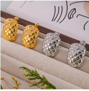 Detailed view of gold and silver geometric quilted pattern stud earrings in titanium steel