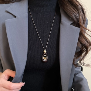Detail of a vintage resin tiger eye oval pendant on a grey suit jacket background
