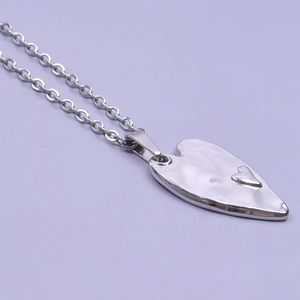 Detailed view of silver heart pendant with hammered texture on a light purple background