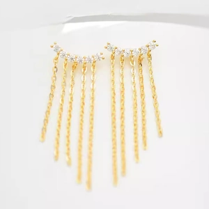 Macro detail of gold tassel earrings featuring sparkling zircon inlay and delicate chain fringes