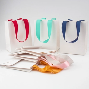 White paper gift bags with colorful ribbon handles shown in open and folded states