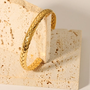 Detailed view of an 18K gold plated knotted bracelet with woven wheat ear texture