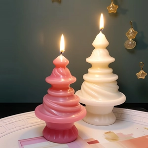 Light pink and cream Christmas tree candles with spiral design lit on a green background