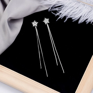 Detail shot of silver snowflake earrings with long sparkling tassel on black velvet