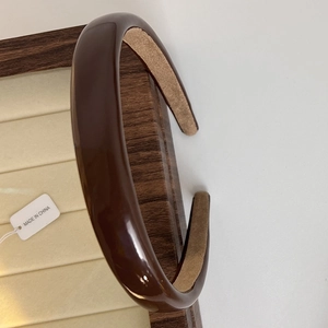 Detail of dark brown glossy headband featuring a non-slip velvet inner lining on wood tray