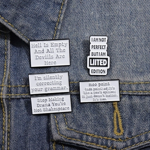 Detail of five minimalist black and white enamel letter pins on a denim jacket