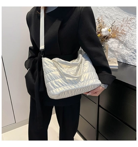 Detail view of pearl white quilted nylon crossbody bag with adjustable wide shoulder strap