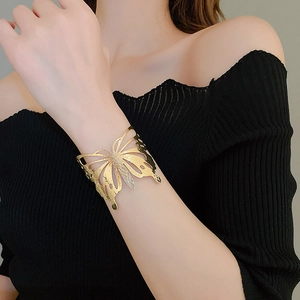 Macro shot of gold butterfly cuff bracelet with hammered texture on black background