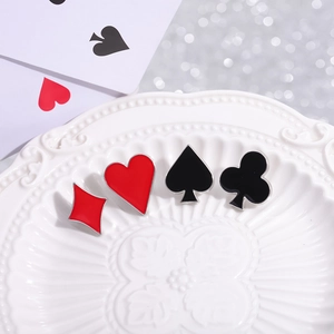 Set of four creative poker suit enamel pins including hearts and spades on a white plate