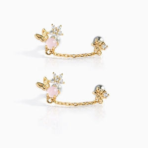 Macro detail of 18K gold butterfly and flower earrings with pink beads and zircon stones