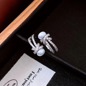 Detailed macro view of silver open ring with double pearls and pavé set cubic zirconia