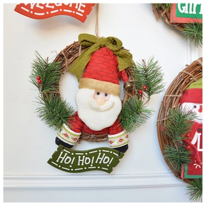 Close-up of Santa plush wreath with pine needles and Ho Ho Ho wooden sign on vine base