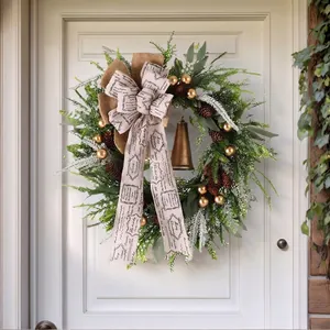 Christmas wreath with pinecones, golden bells and ribbon hanging on a white wooden door