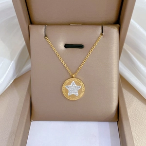 Gold star pendant necklace with crystal inlay on a brown jewelry display case
