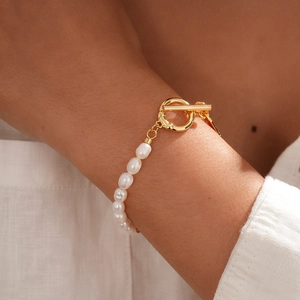 Macro shot of a baroque pearl bracelet with a golden T-bar closure worn on a wrist