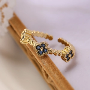 Detail of 18K gold plated clover ring with dark blue zircon and beaded texture