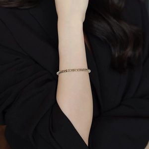 Detail of elegant gold textured beaded bracelet on model wearing black professional attire