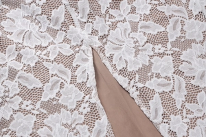 Macro shot of white floral lace fabric with mesh texture and beige lining details