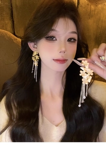 Detailed close-up of long tassel floral earrings with crystal droplets on a model