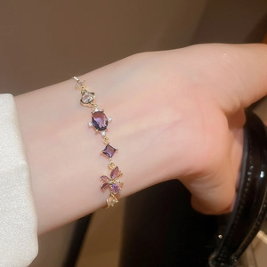 Detailed shot of gold butterfly bracelet with purple and white cubic zirconia on wrist