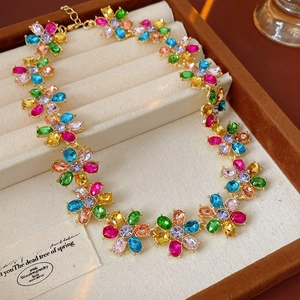 Close-up of golden necklace with colorful crystal flower charms in a beige jewelry box