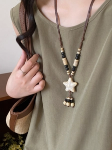 Macro shot of boho star pendant with bead tassels on a woven brown rope necklace
