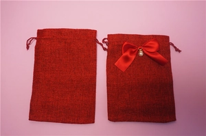 Dettaglio di sacchetti regalo in lino bordeaux con coulisse, fiocchi di raso e perle